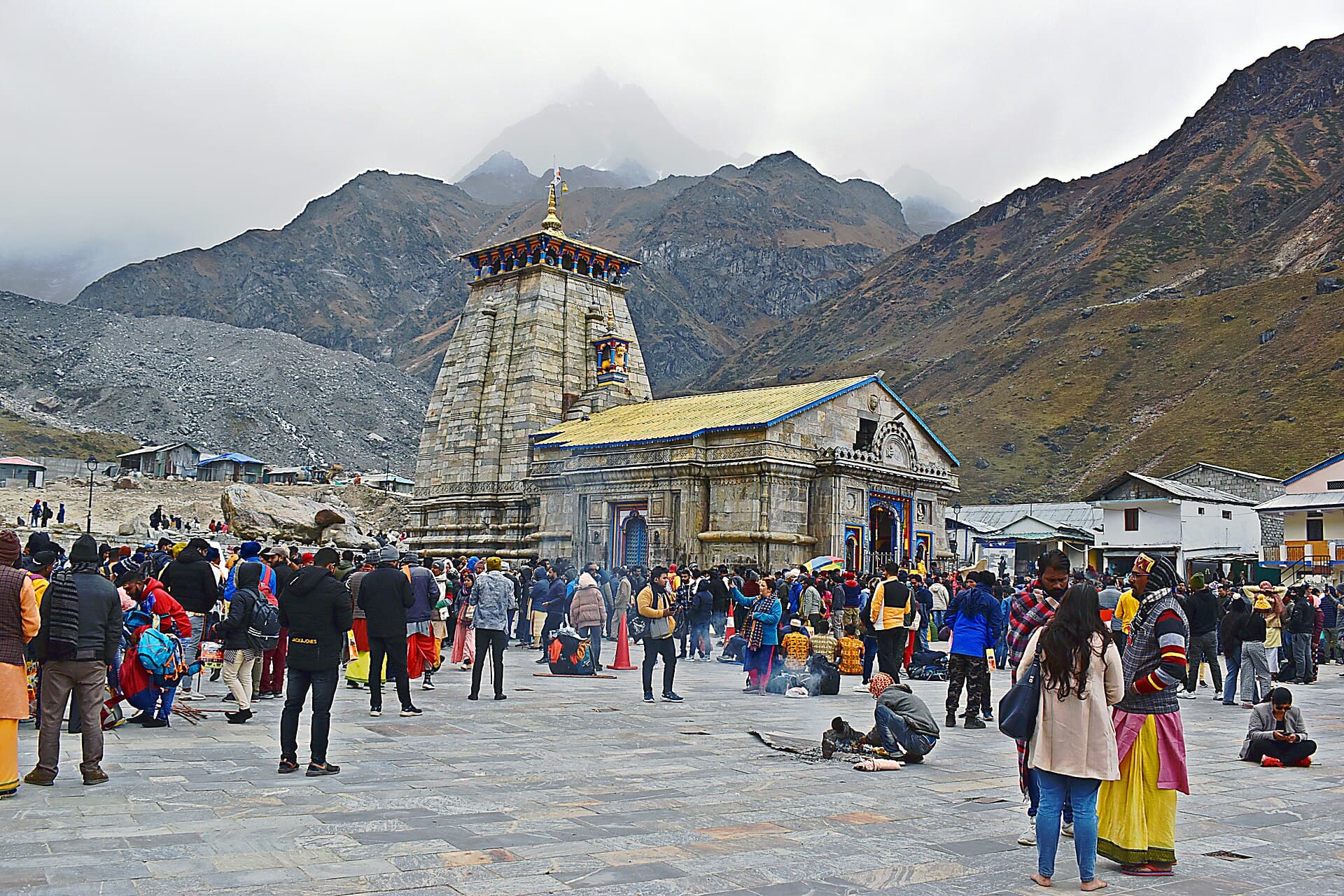 The Kedarnath temple beneath cloud-wrapped peaks, the courtyard filled with pilgrims