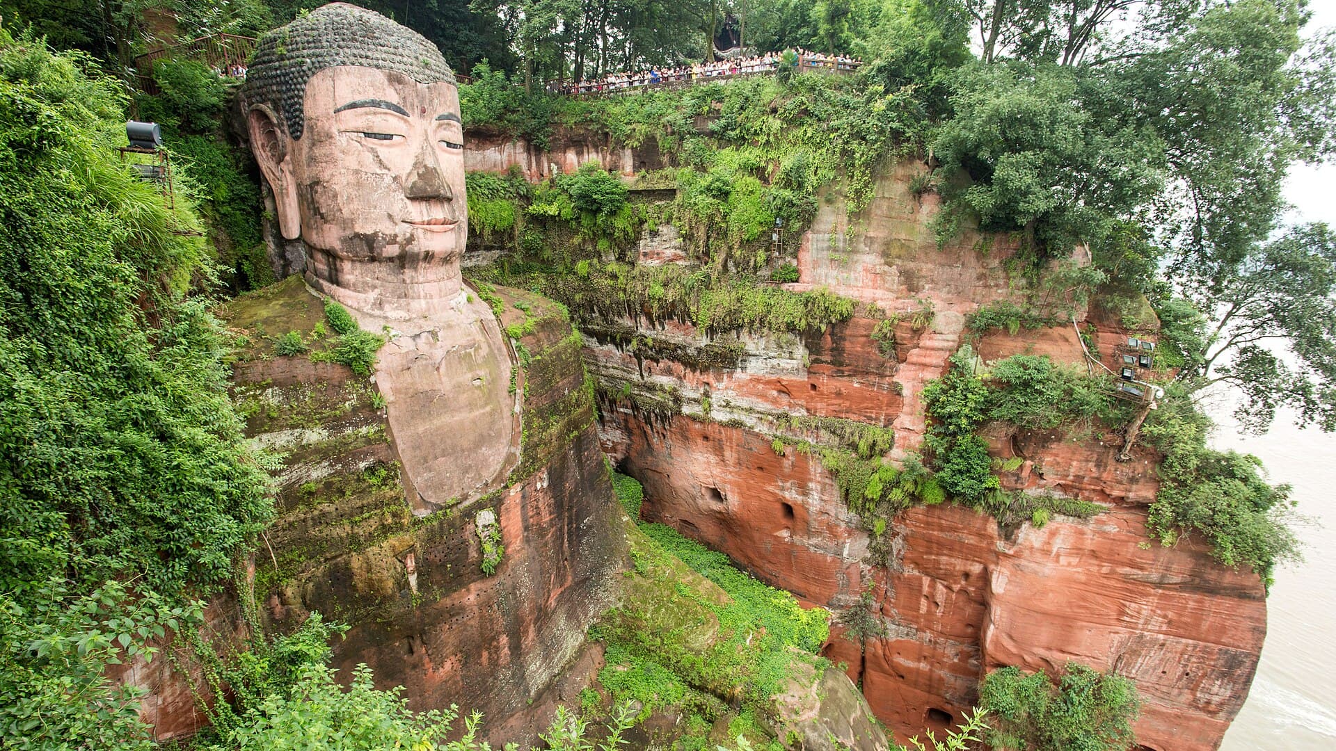 A colossal stone Buddha, itself a cliff