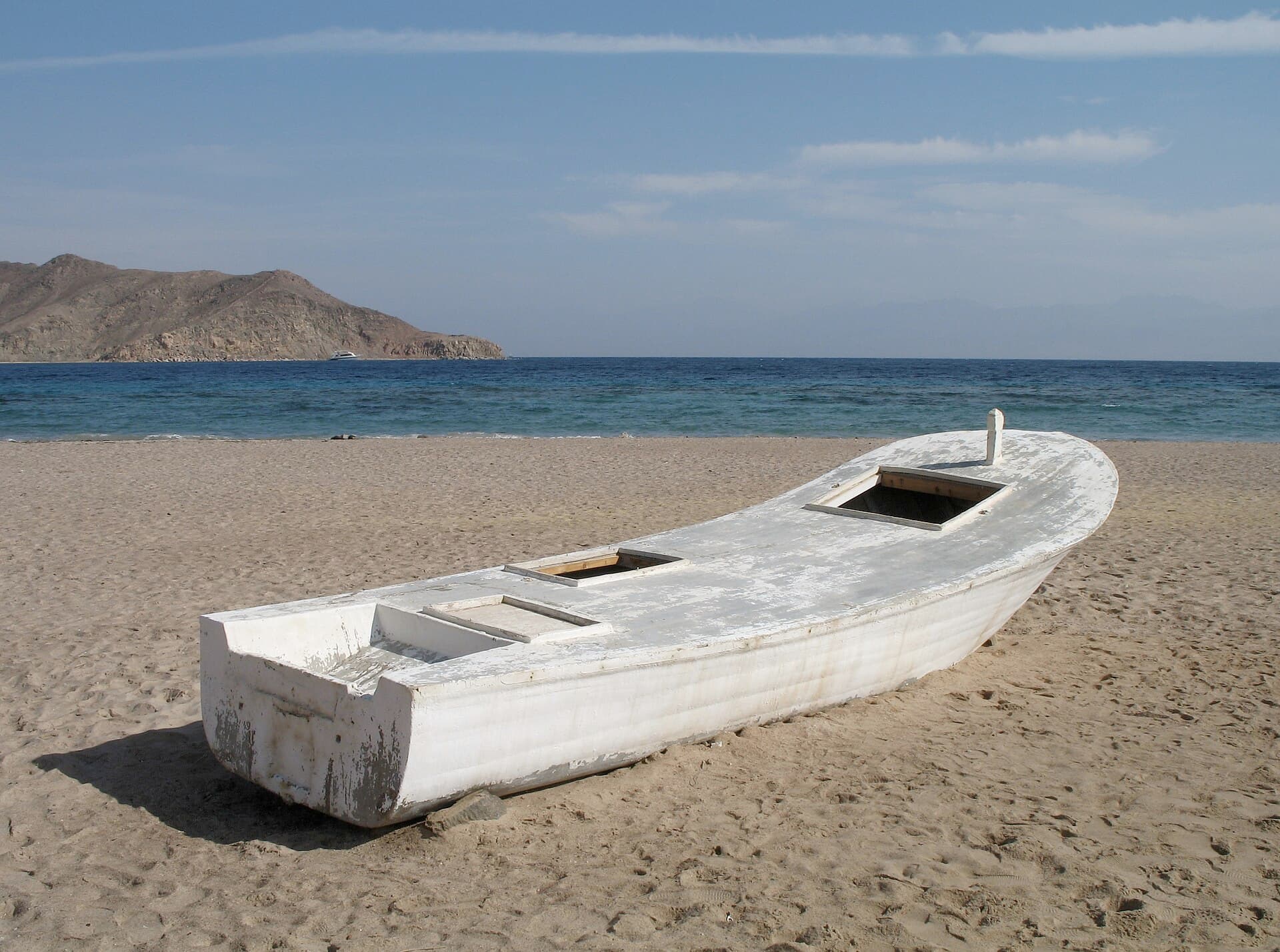 An old boat on an empty shore, the morning open to the sea