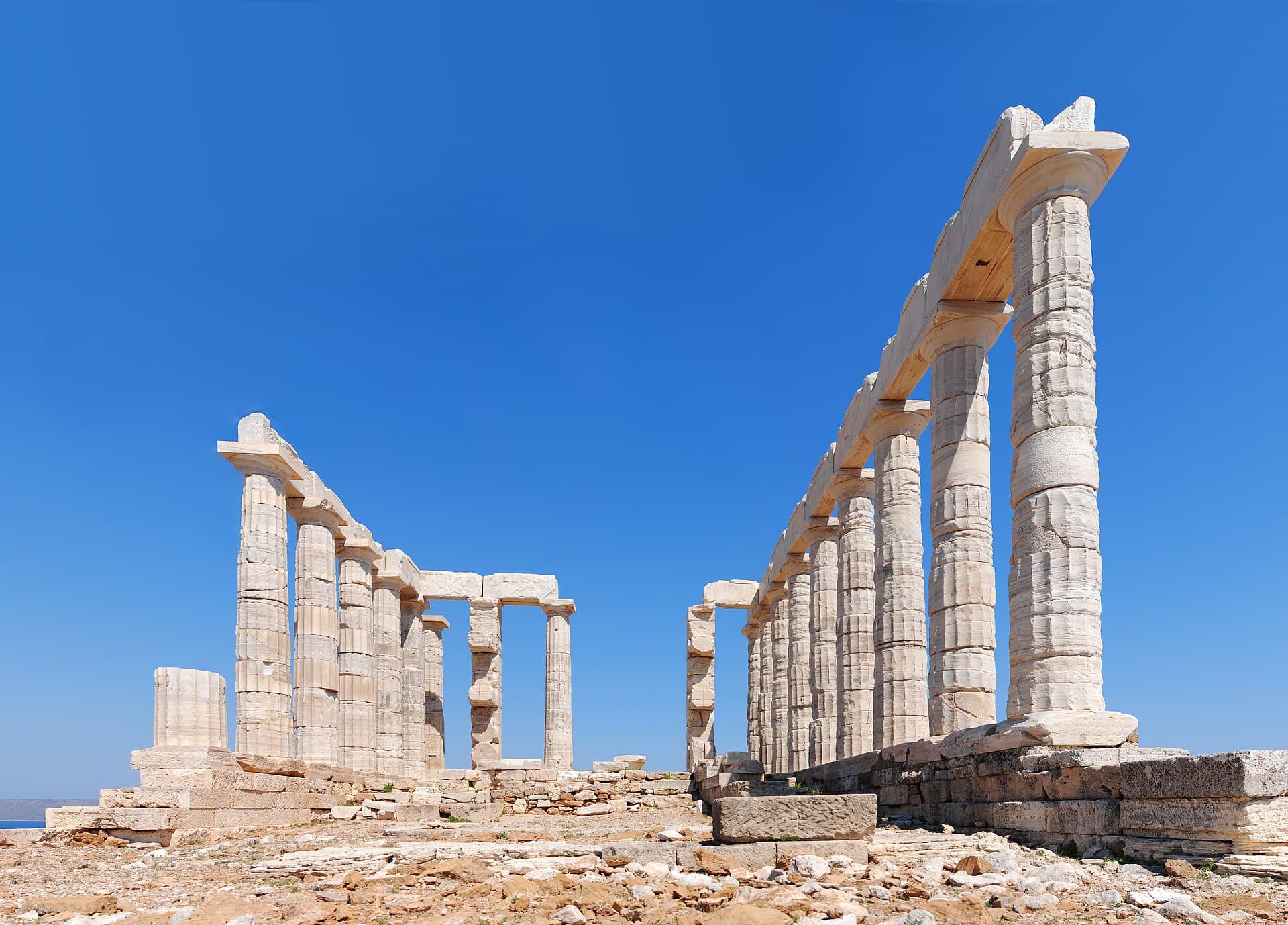 The white marble columns of the Temple of Poseidon gleaming against a blue sky