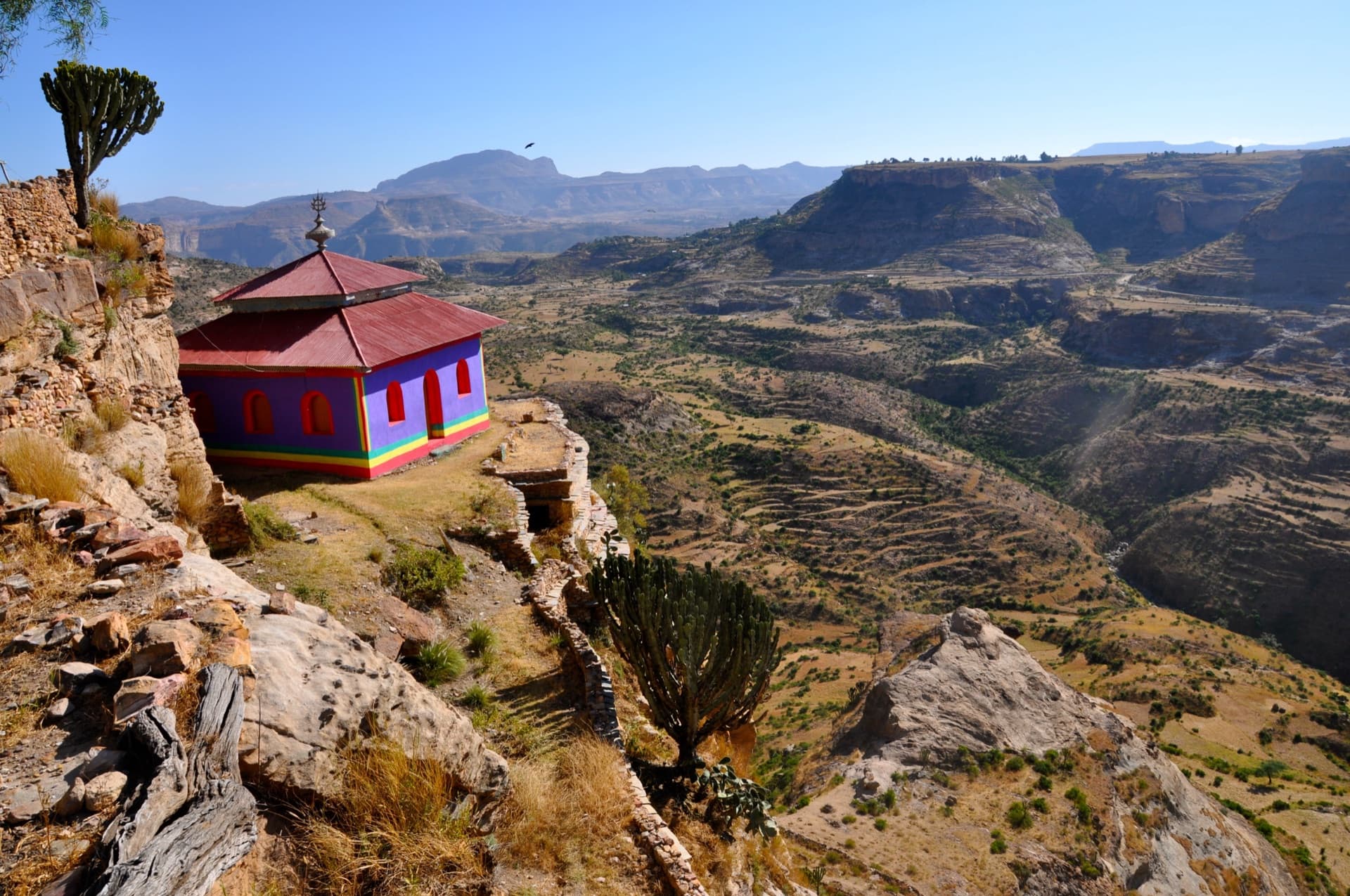 A brightly painted chapel at the cliff edge of the Debre Damo amba, the Tigray highlands far below