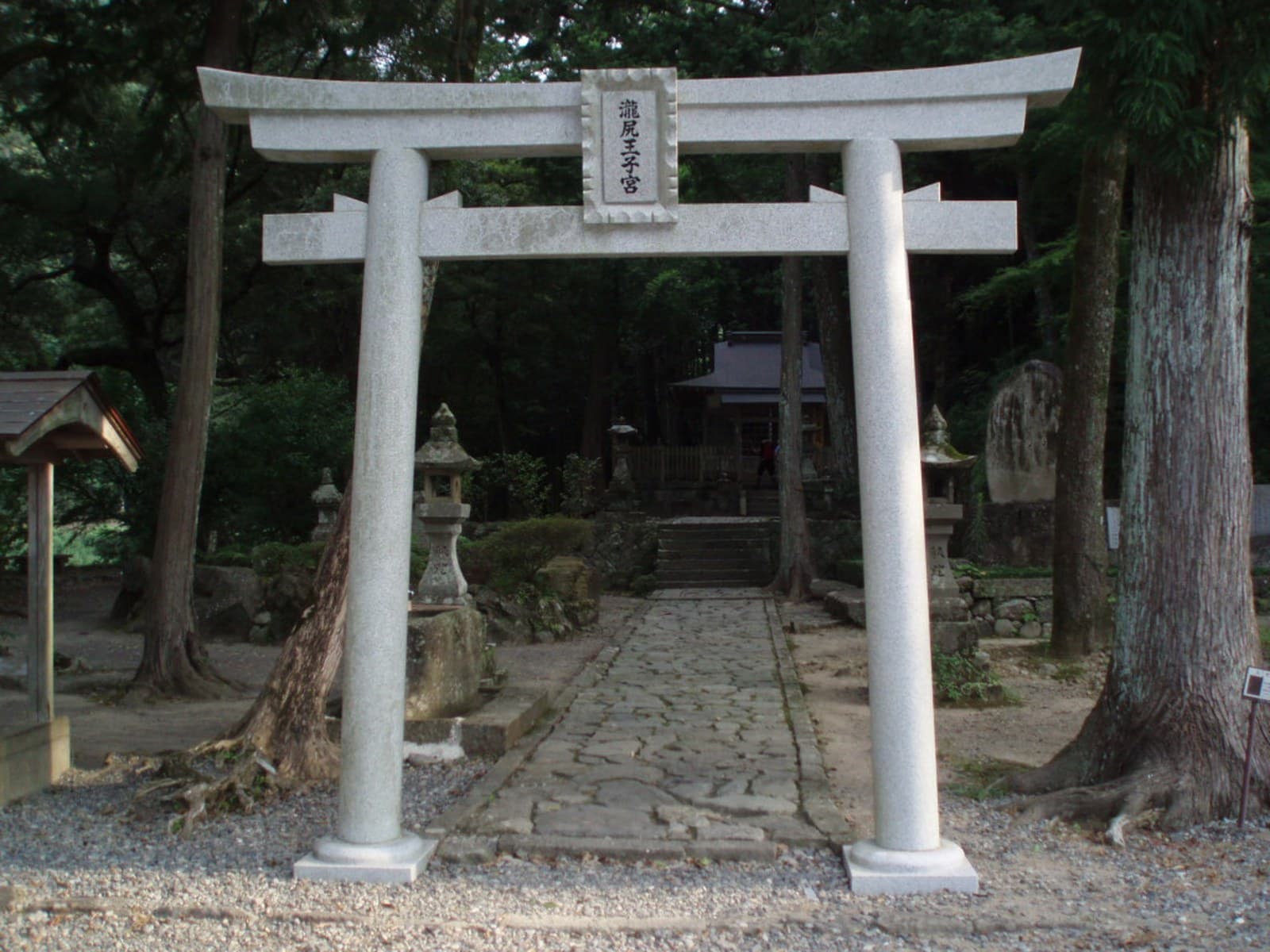 The stone torii of Takijiri-oji framing the shrine among the cedars