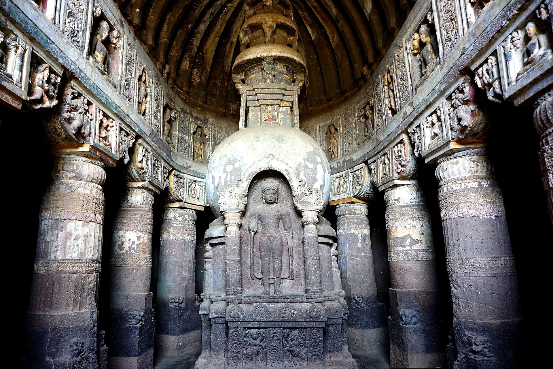 A chaitya hall lined with rock-cut pillars and a stupa carved with the Buddha