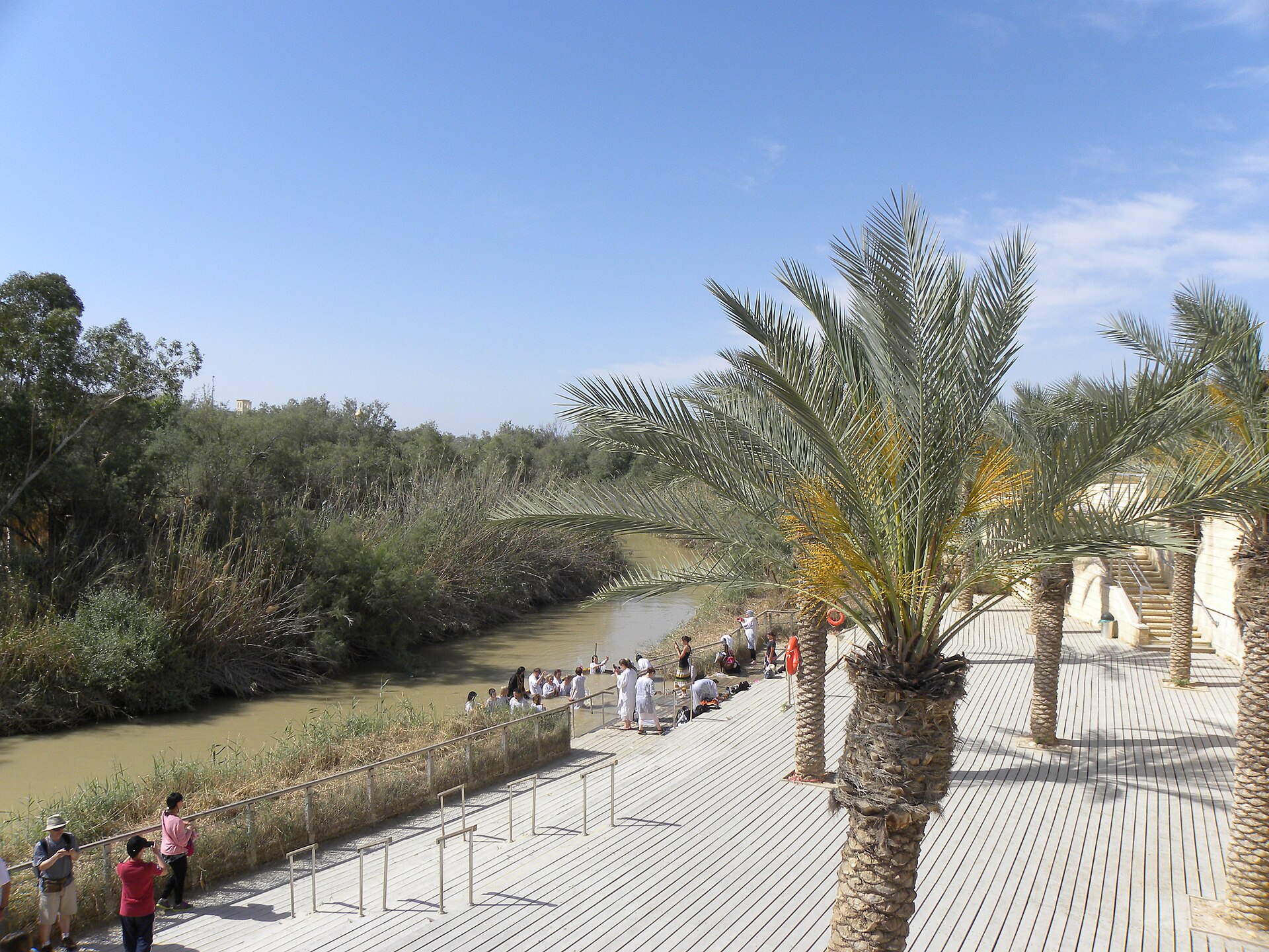 White-robed pilgrims receiving baptism in the Jordan River