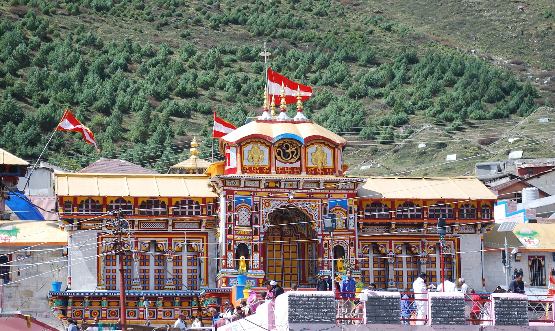 Badrinath temple against a dark forested mountainside