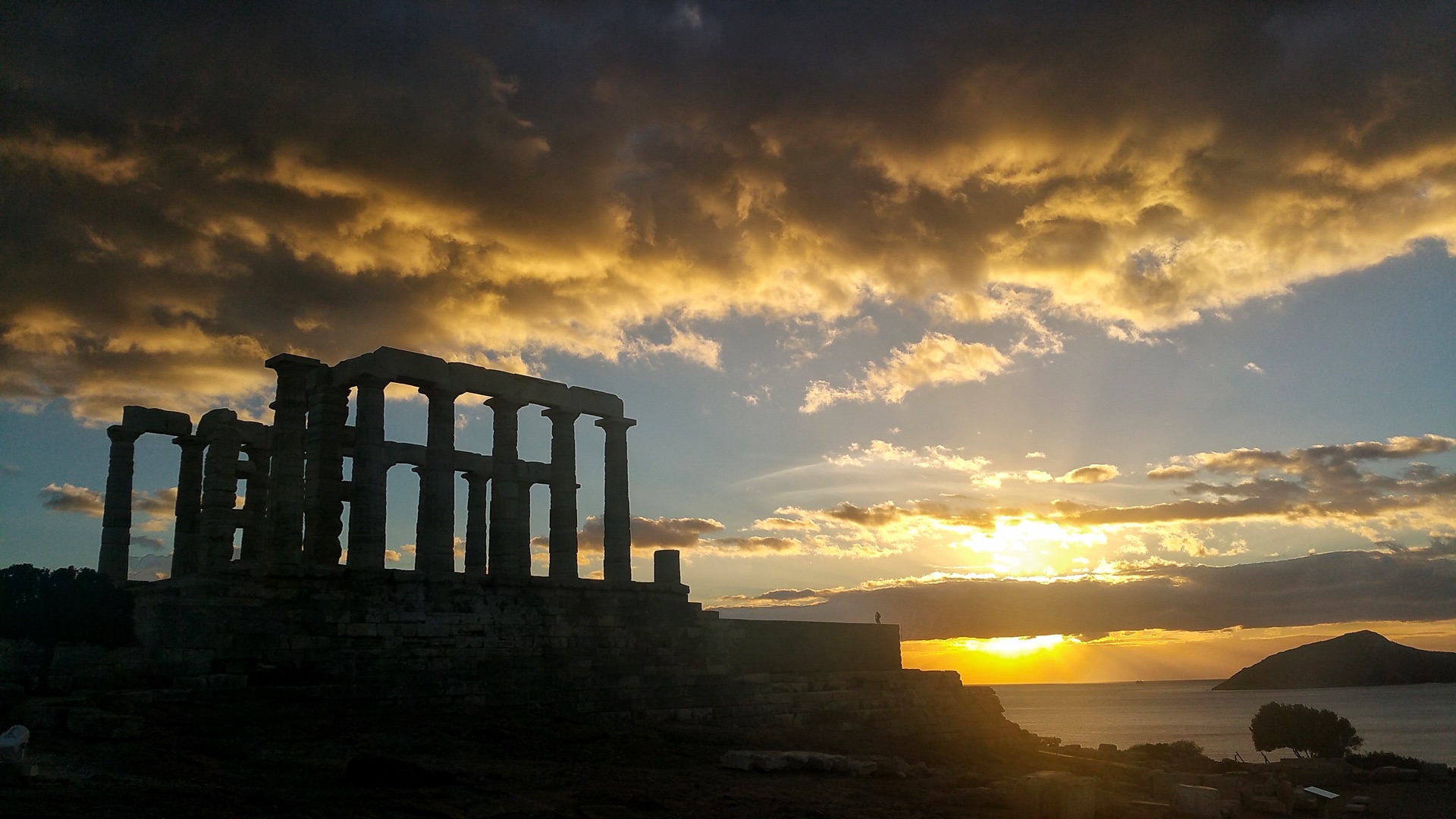 The Temple of Poseidon silhouetted against the sun setting over the Aegean
