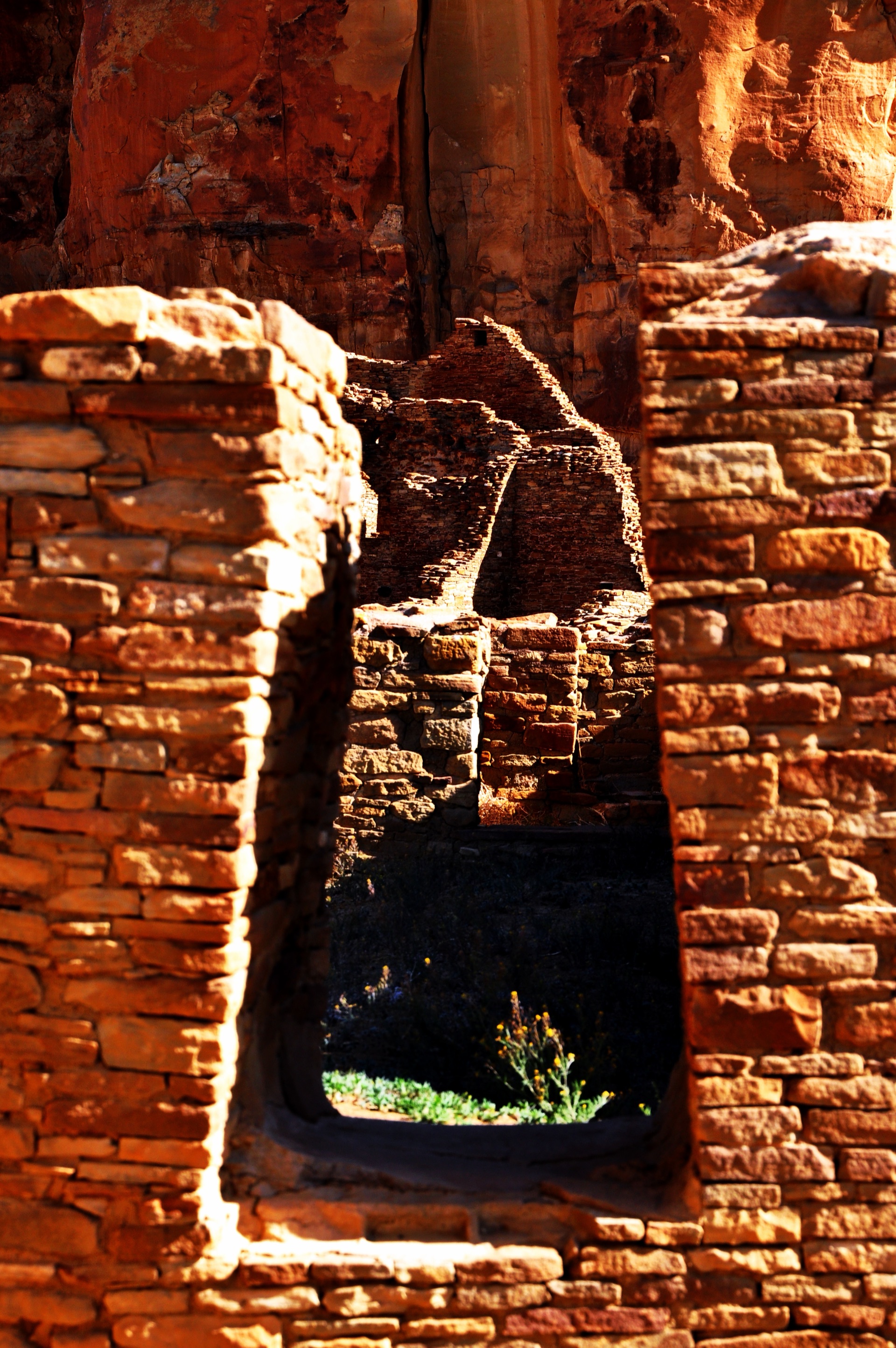 Golden Chacoan masonry and the sandstone cliff seen through a stone doorway