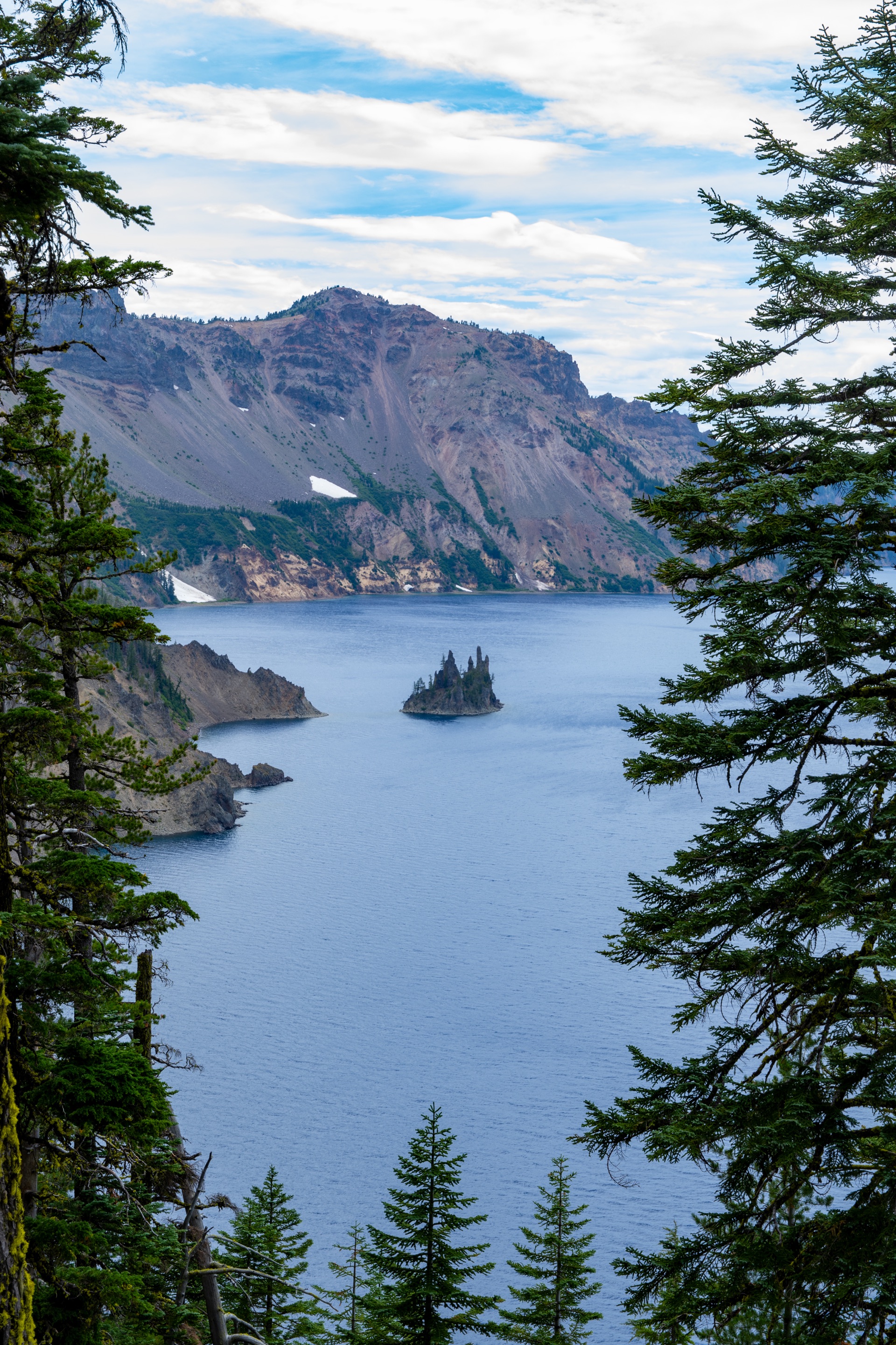 The Phantom Ship rock islet rising from deep-blue Crater Lake, seen through the pines