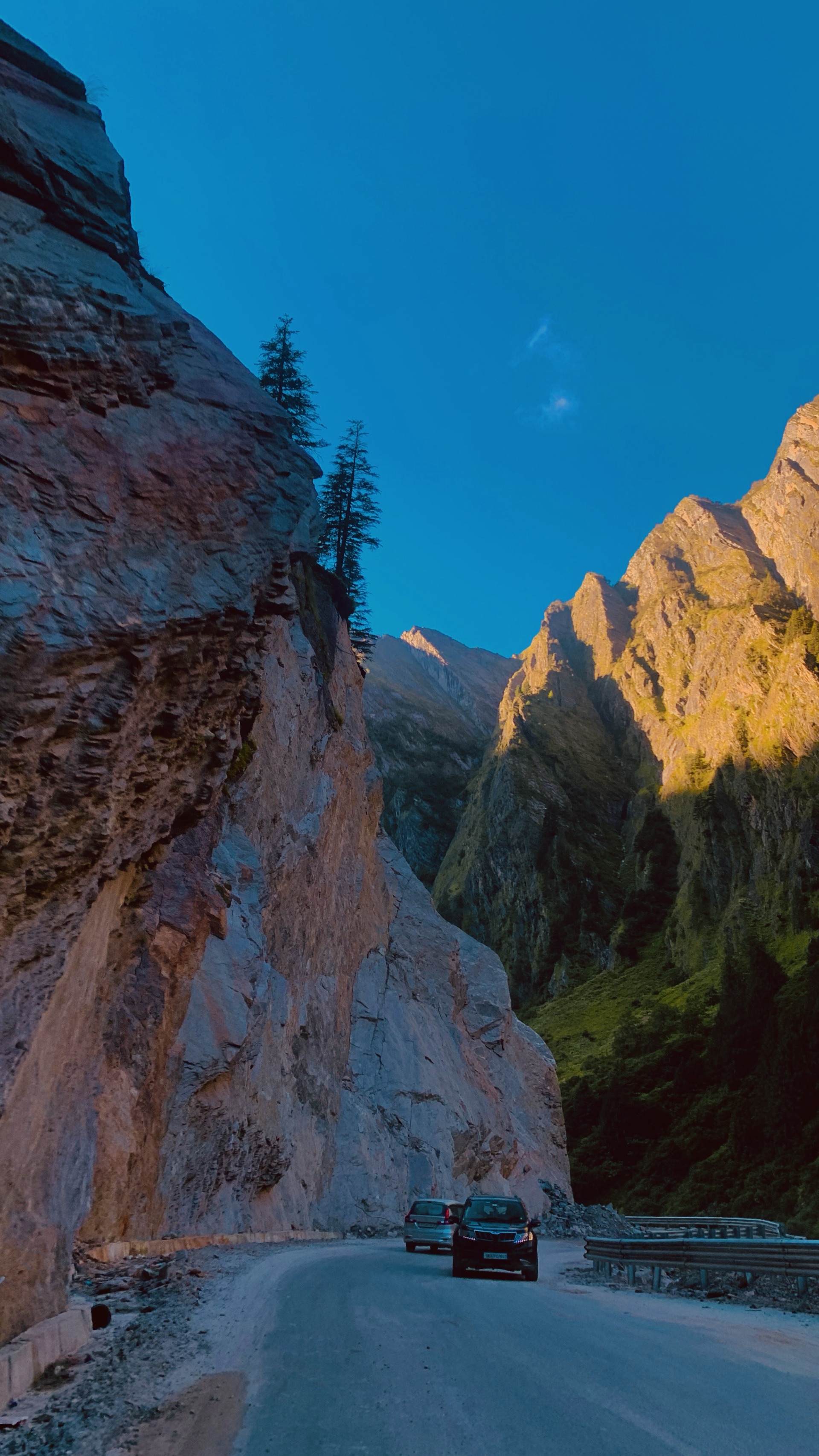 A Himalayan gorge lit by evening sun on the peaks, the mountain road climbing to Gangotri