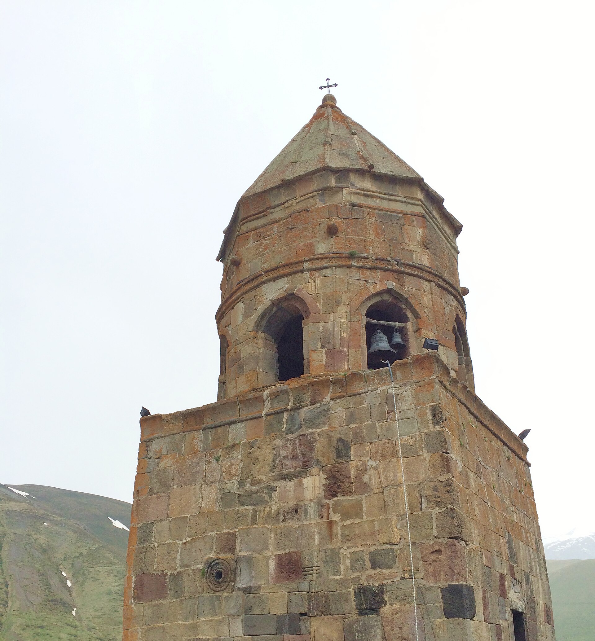 The stone bell tower of Gergeti Trinity Church, bells hanging in its arches