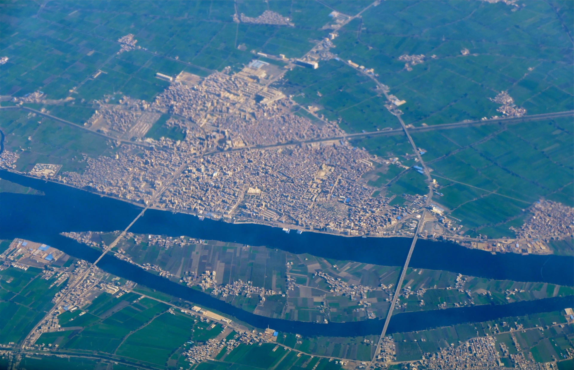 An aerial view of a Nile Delta town, green fields stretching to the horizon