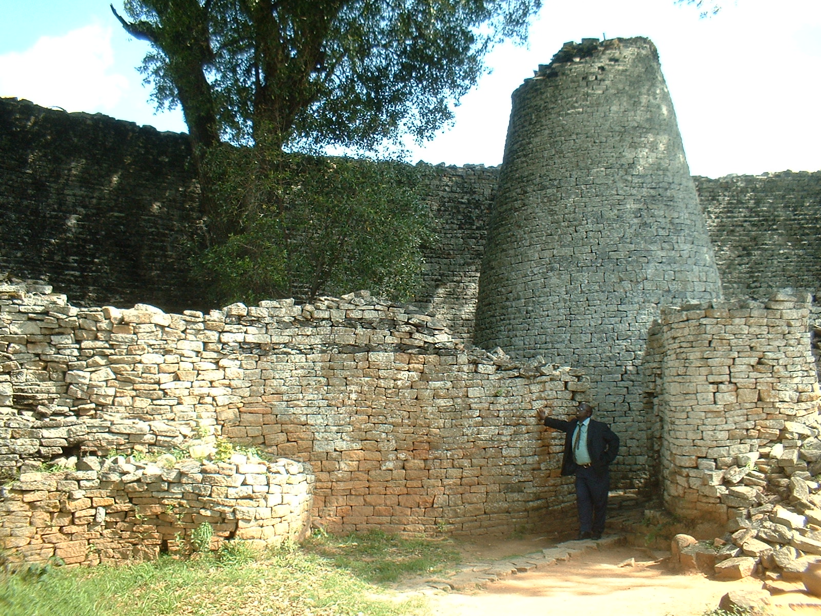 The solid conical tower rising within the curving enclosure wall
