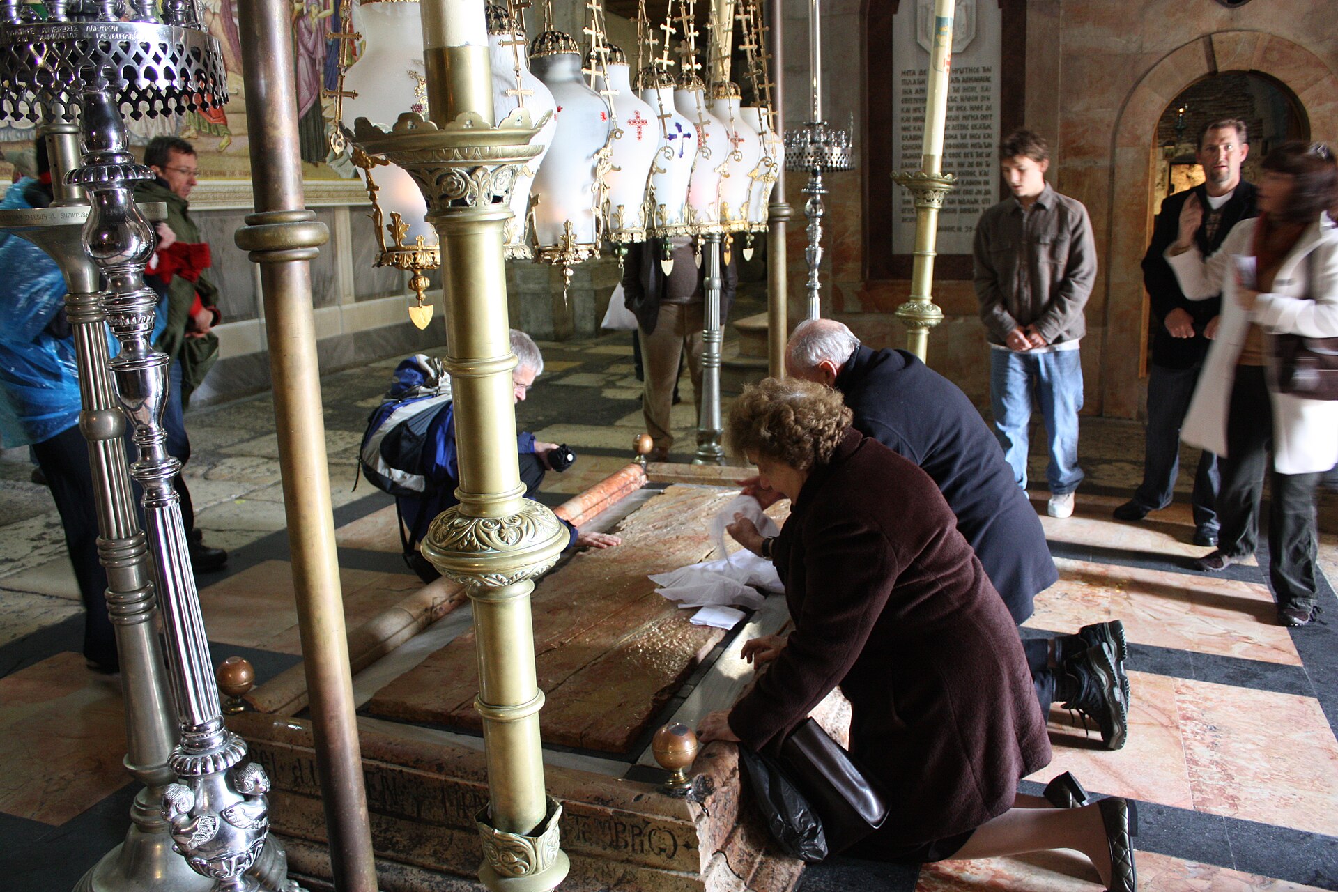 Pilgrims kneeling to press cloths to the Stone of Anointing