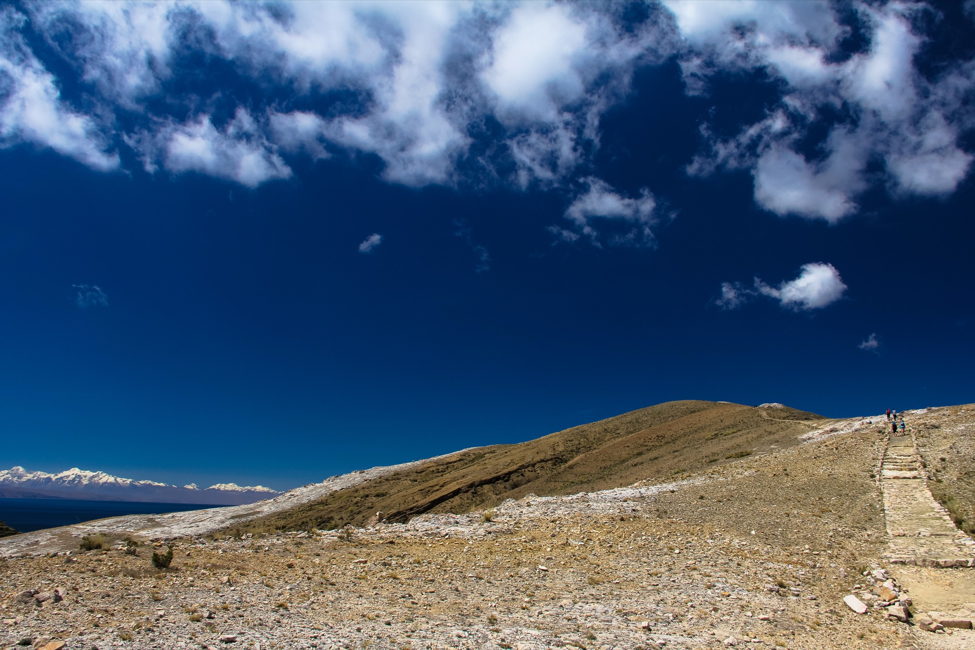 A stone path along the island's ridge, the snow-capped Andes beyond Lake Titicaca
