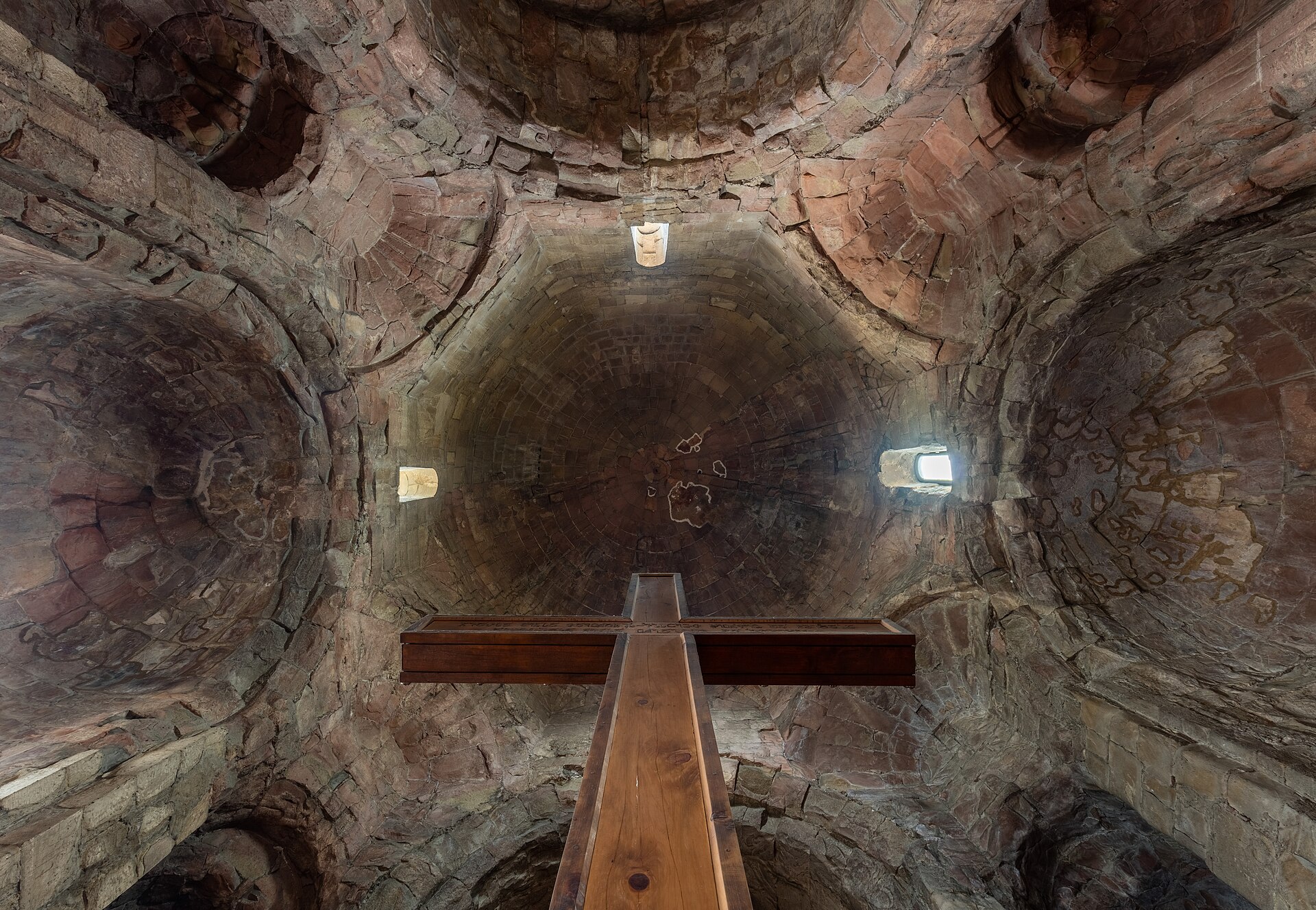 Inside Jvari Monastery, a wooden cross rising toward the stone dome