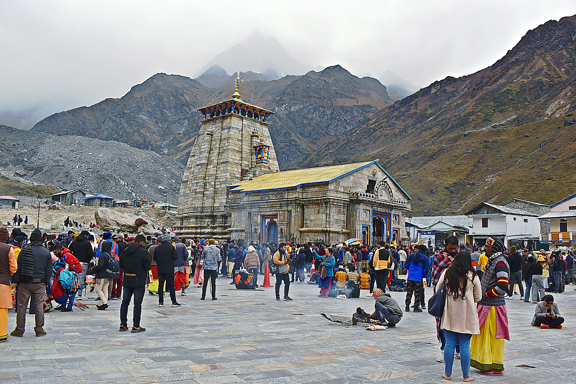 The Kedarnath temple beneath cloud-wrapped peaks, the courtyard filled with pilgrims