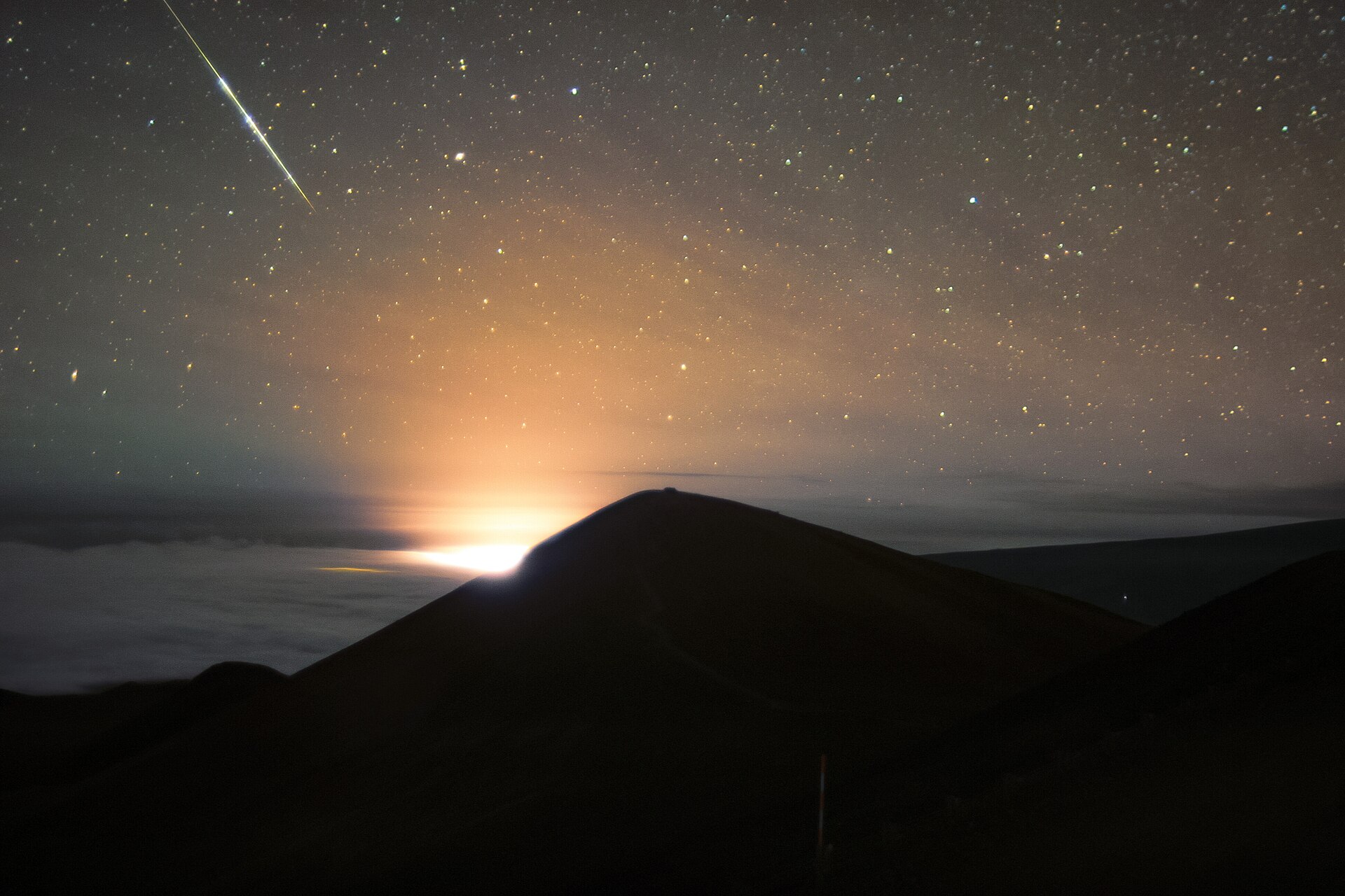 The eruption glowing red beneath a sky full of stars