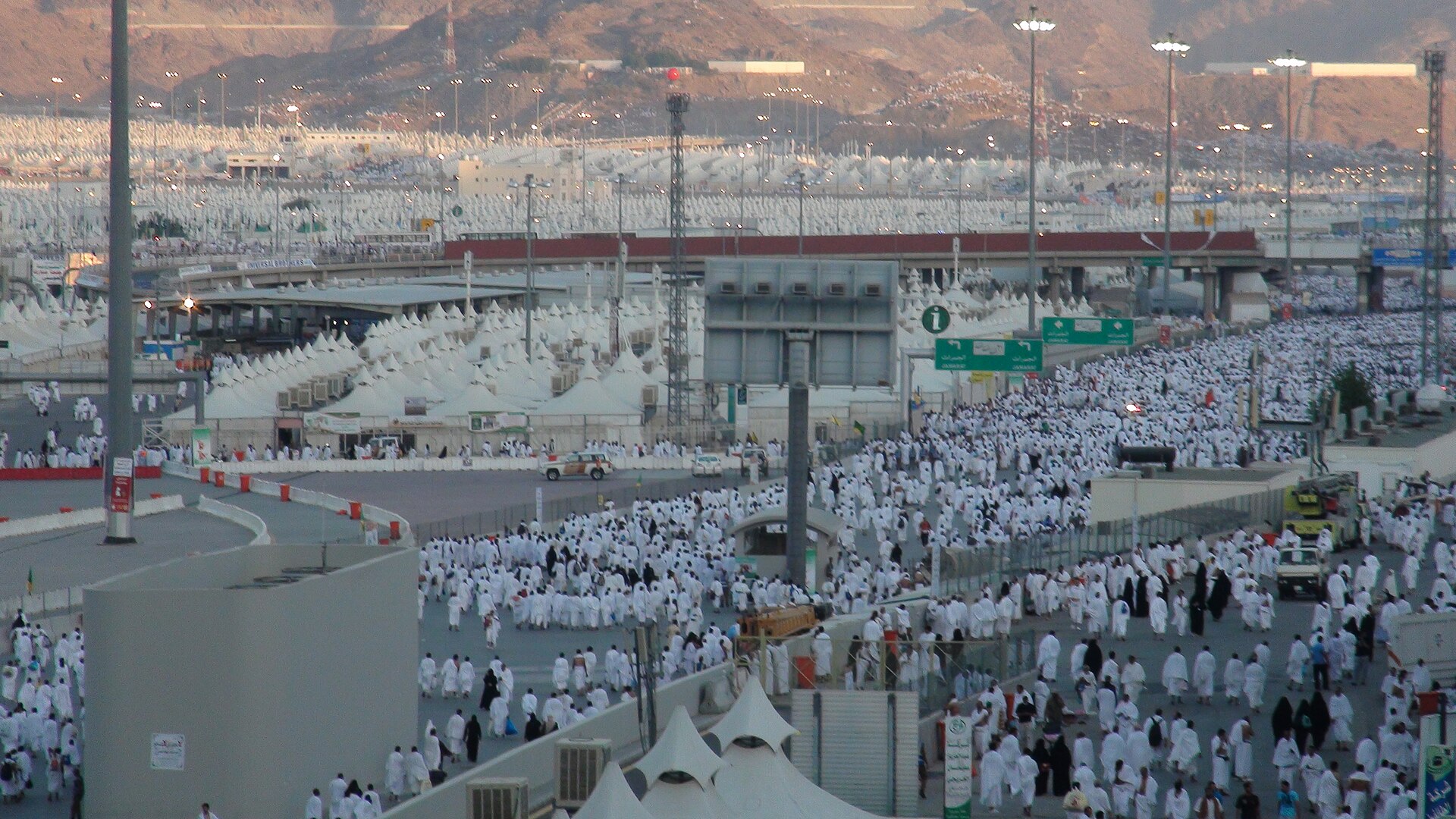 A procession of white-robed pilgrims and the tent city heading toward the Jamarat