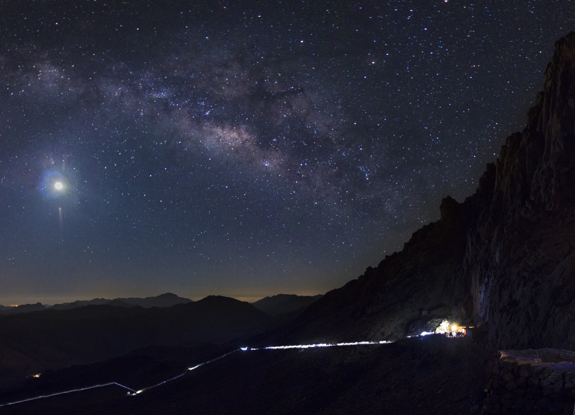 The Milky Way arching over Mount Sinai and the lamps of pilgrims climbing in the dark