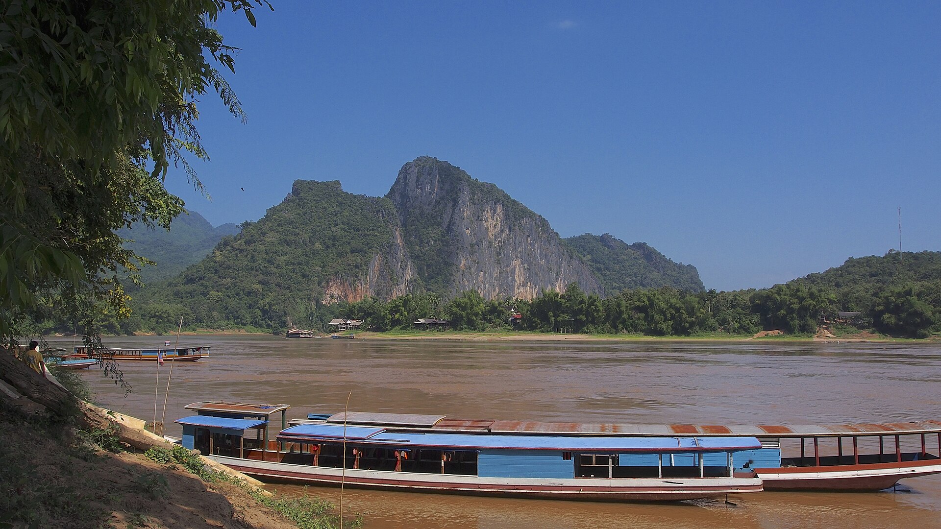 Boats moored on the Mekong beneath the limestone cliff at the Pak Ou landing