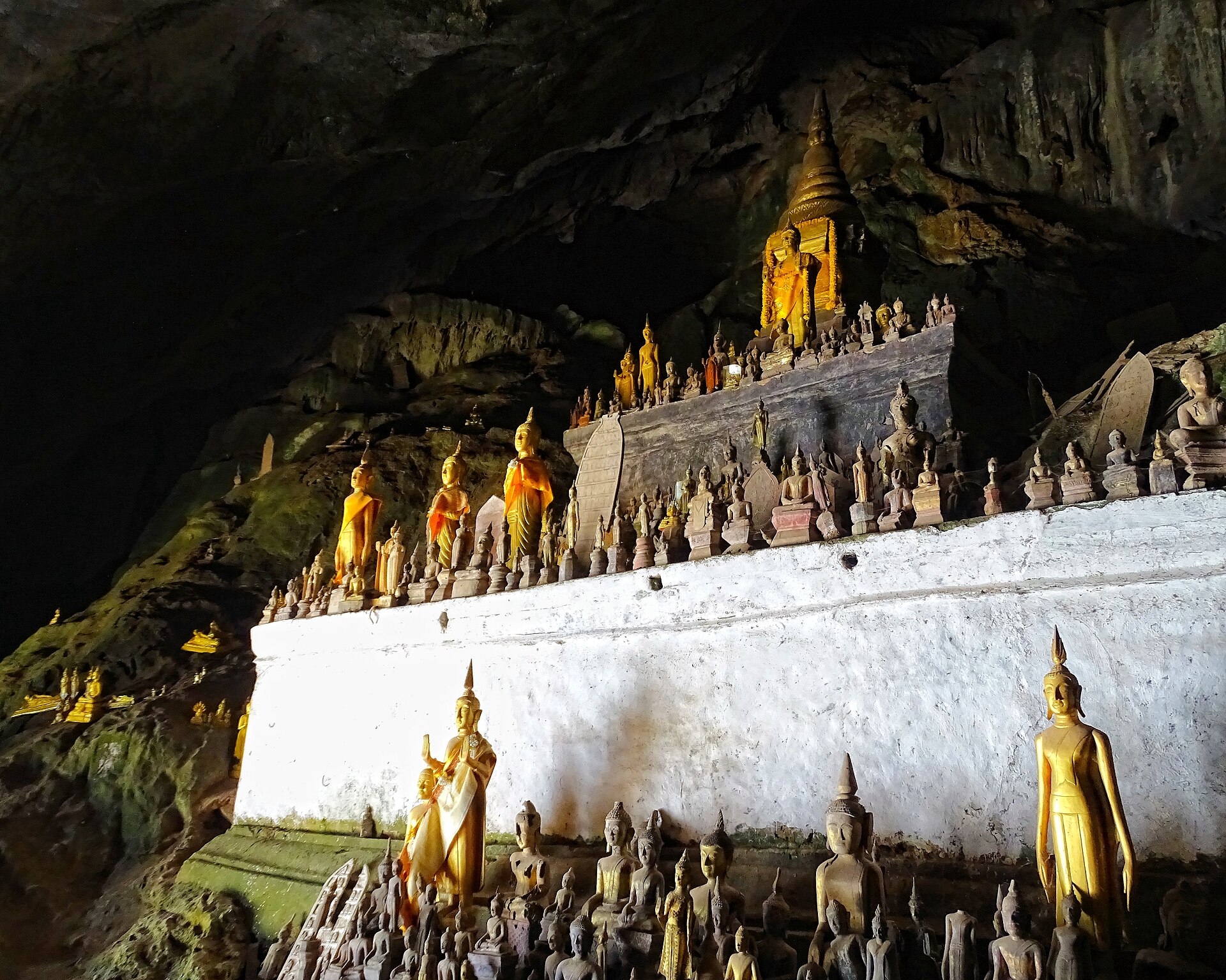 Buddhas great and small standing tier upon tier in the dimness of the Pak Ou caves