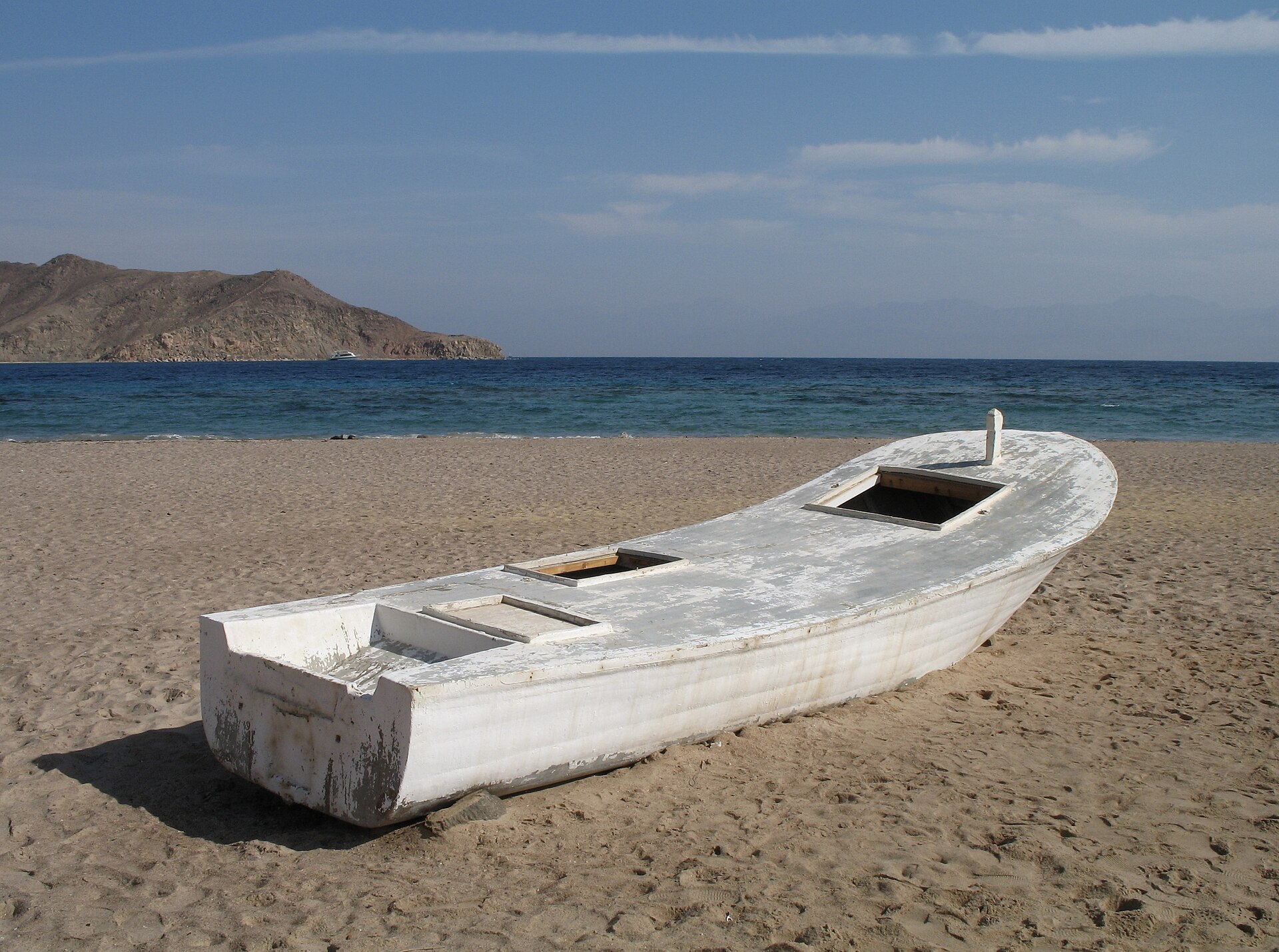 An old boat on an empty shore, the morning open to the sea
