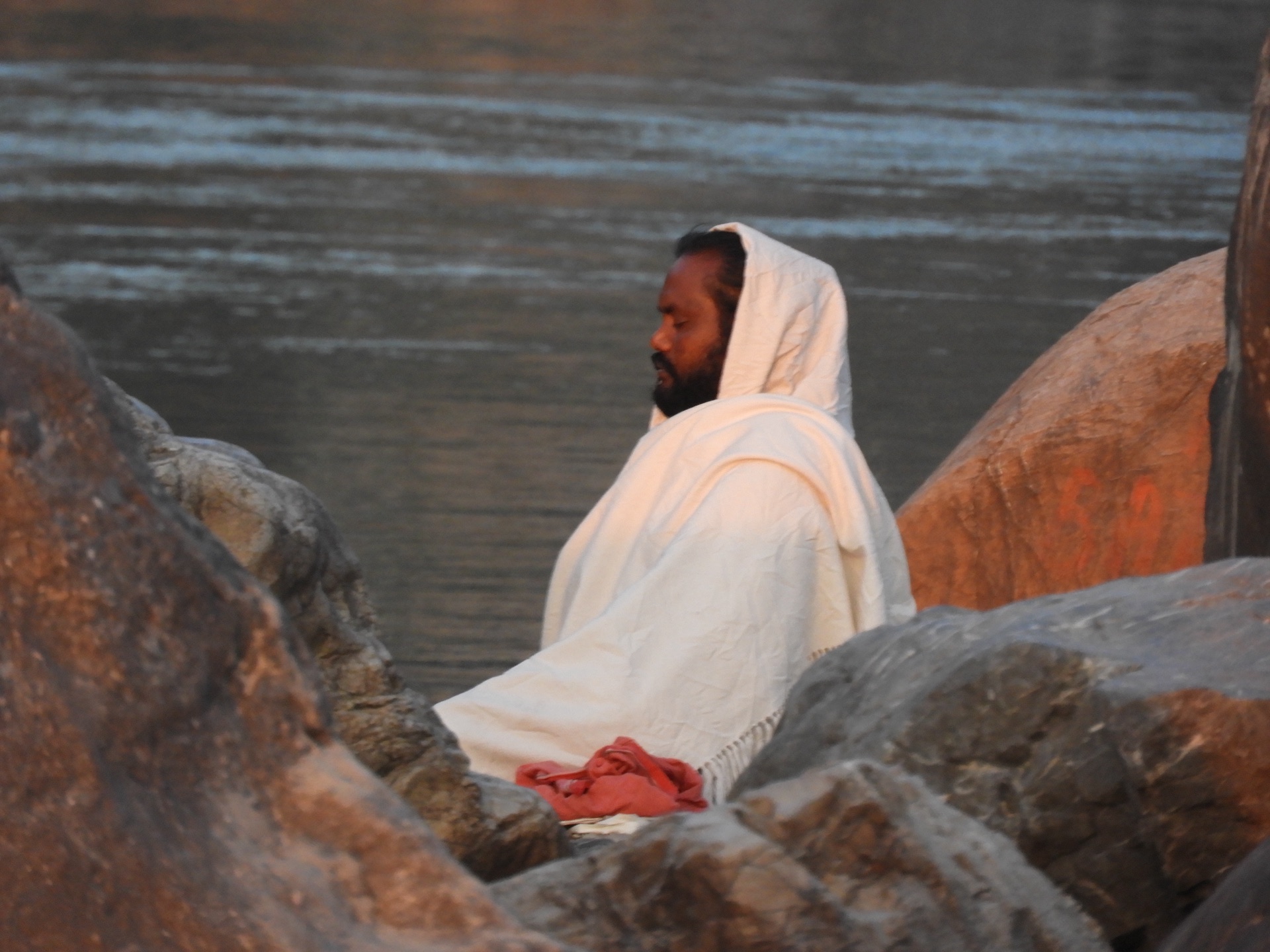 A sadhu seated in meditation on a boulder by the Ganga