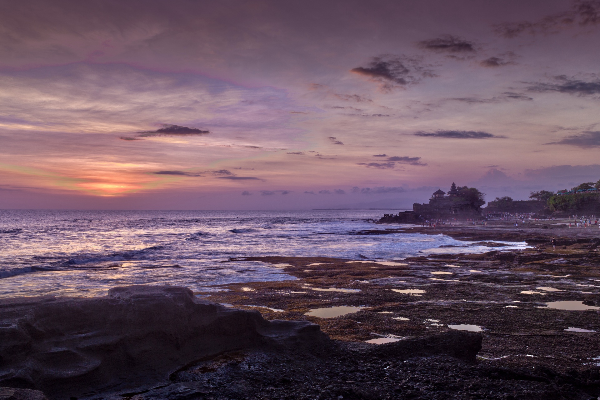 Tanah Lot temple on its rock under a twilight sky, tide pools in the foreground