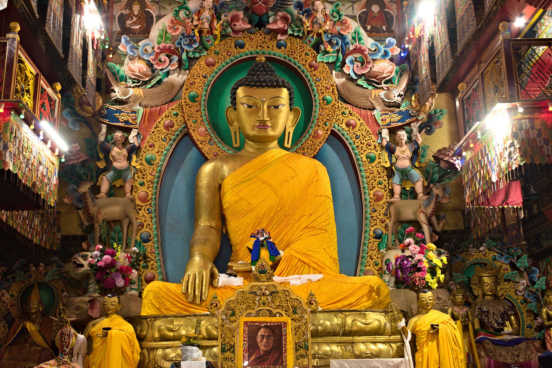 The great Buddha of Tawang Monastery in yellow robes before a golden halo