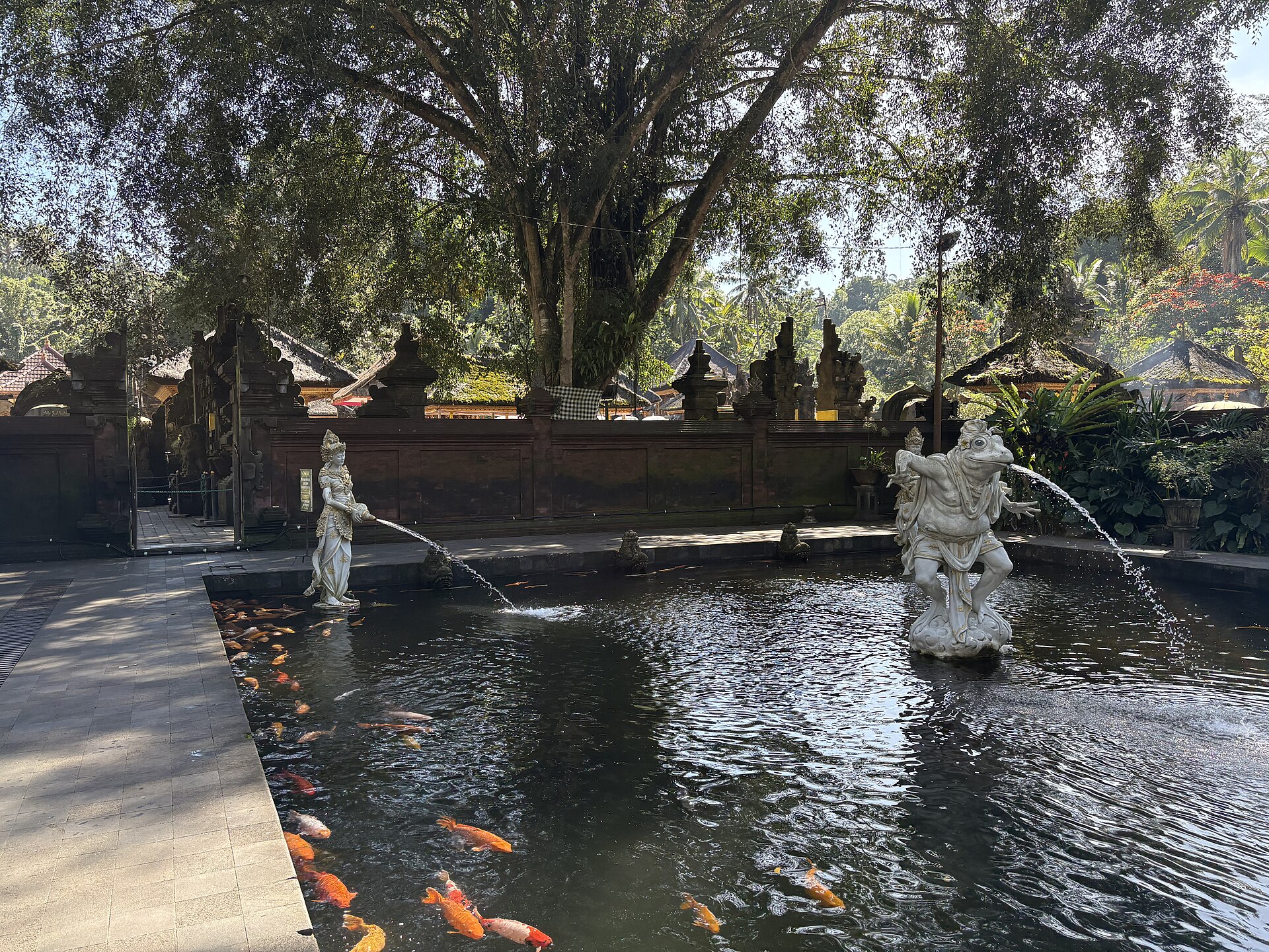 A stone figure spouting holy water into the koi pond