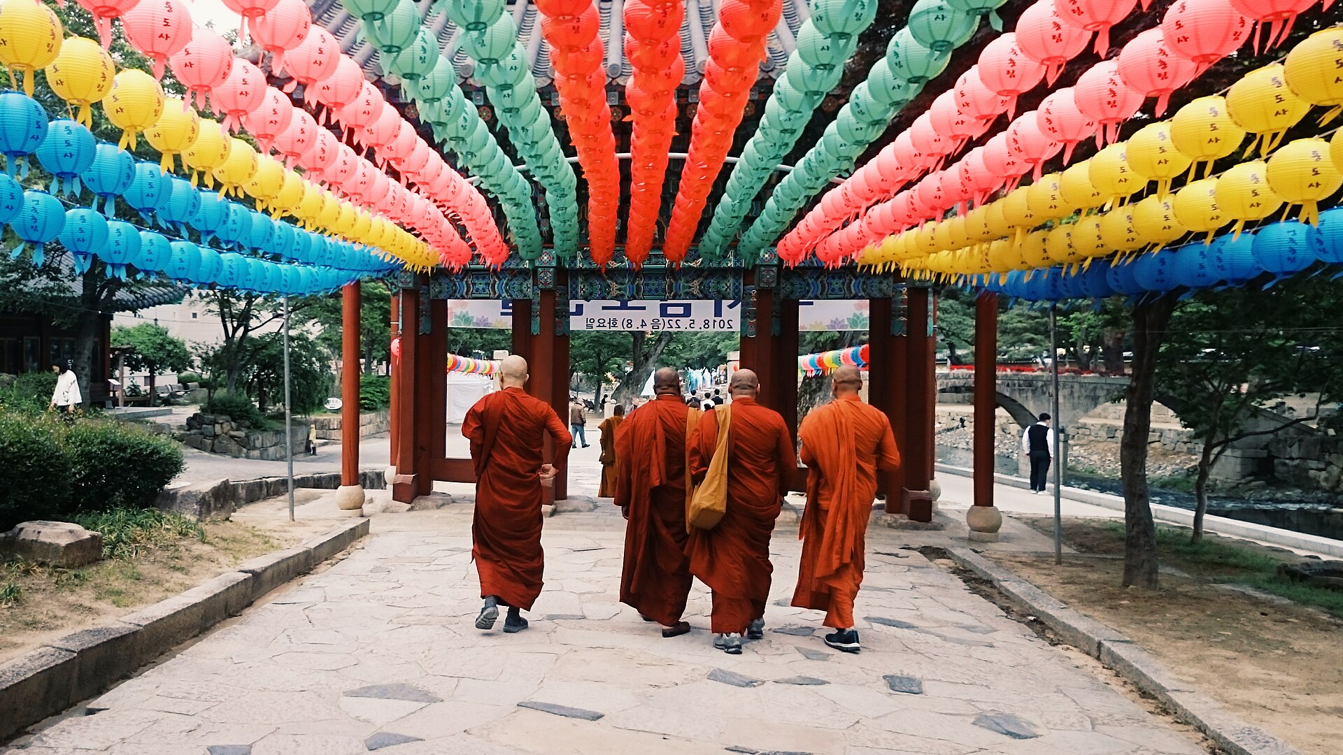 Monks walking beneath a wave of colorful lotus lanterns