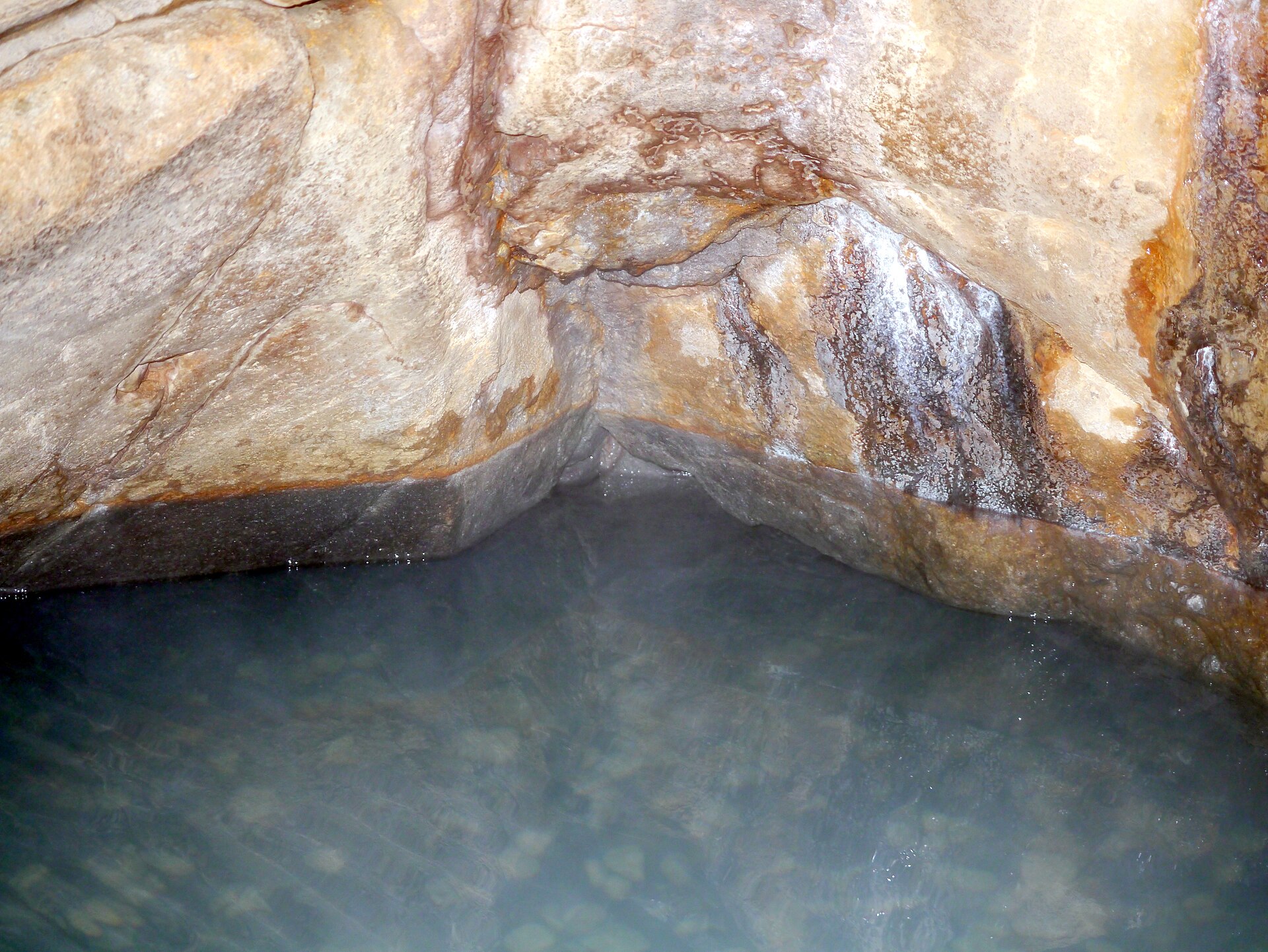 Mineral-stained rock cupping the milky water of the spring